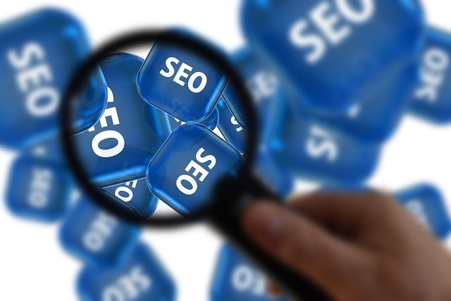 Lupa zaostřená na modré kostky s nápisem SEO jako ilustrace zkoumání optimalizace pro vyhledávače.